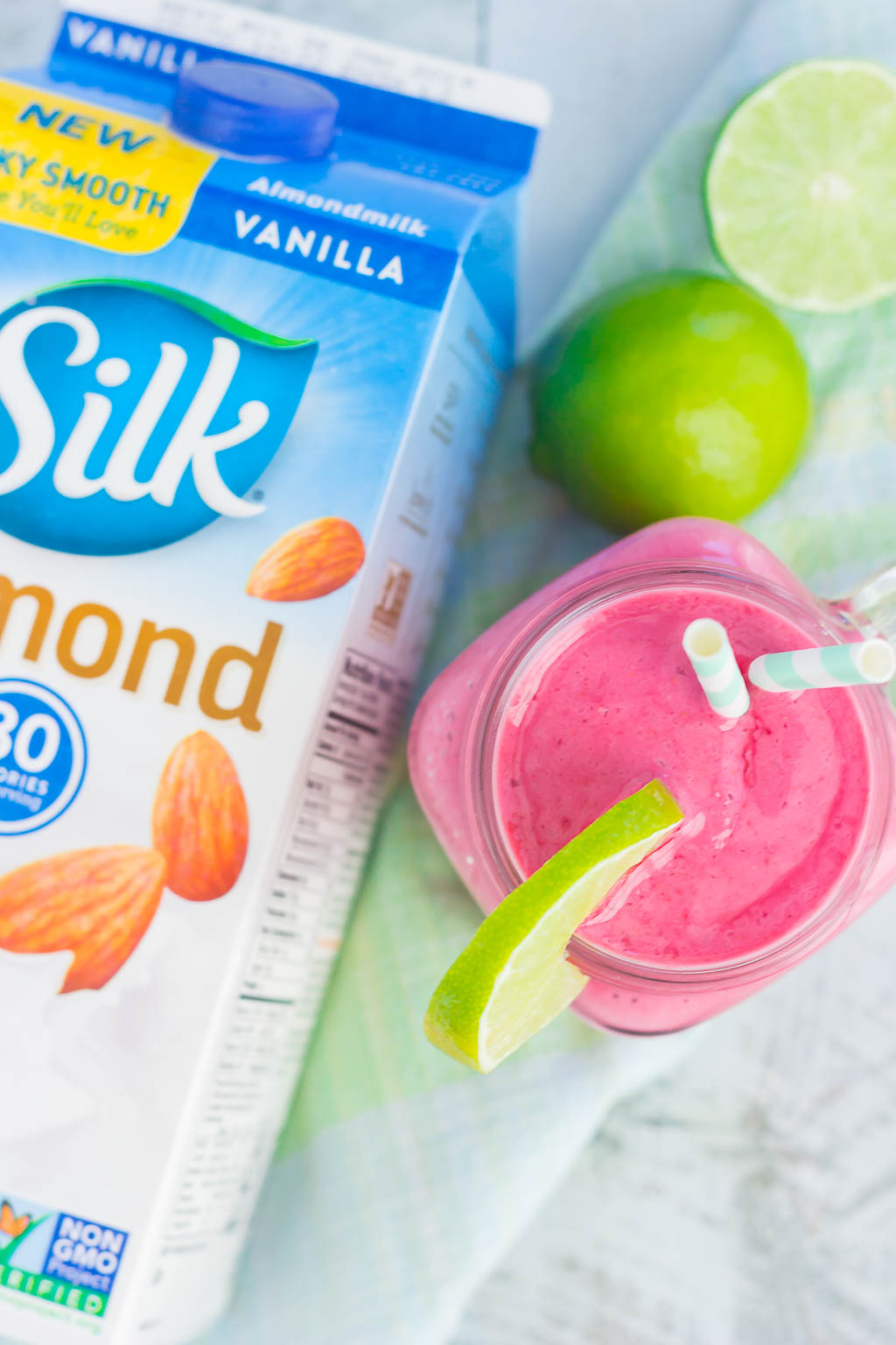 overhead view of lime raspberry smoothie next to carton of almond milk