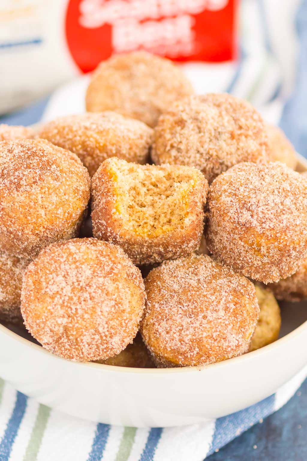 cinnamon sugar baked donut holes piled in a white bowl 