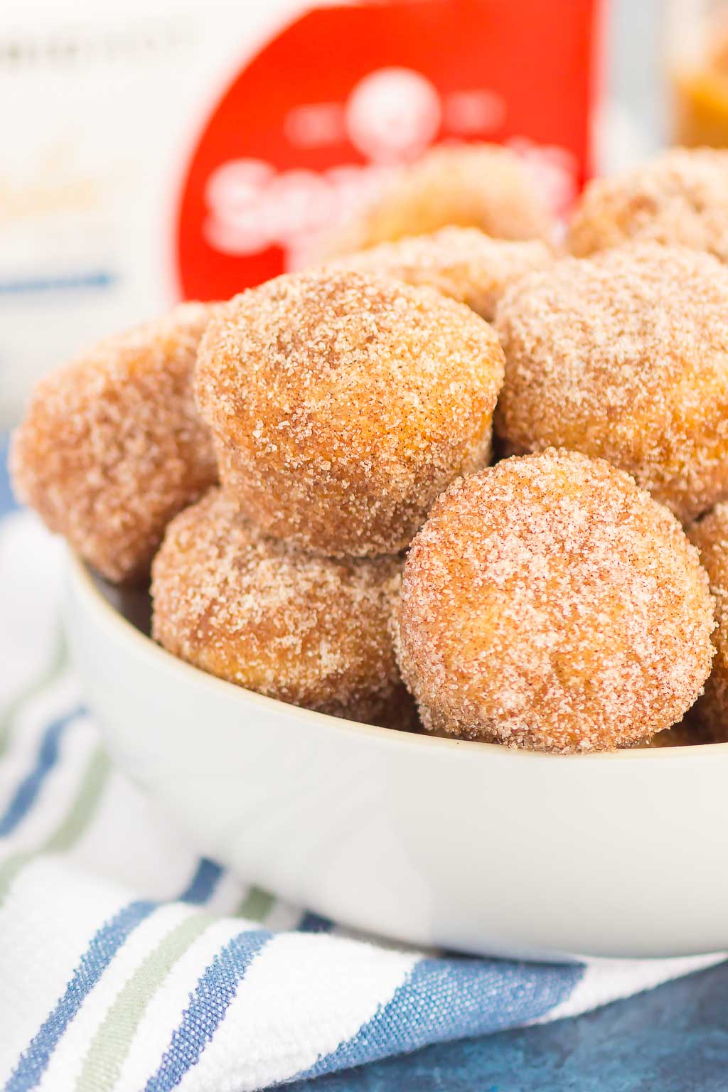 cinnamon sugar baked donut holes piled in a white bowl 