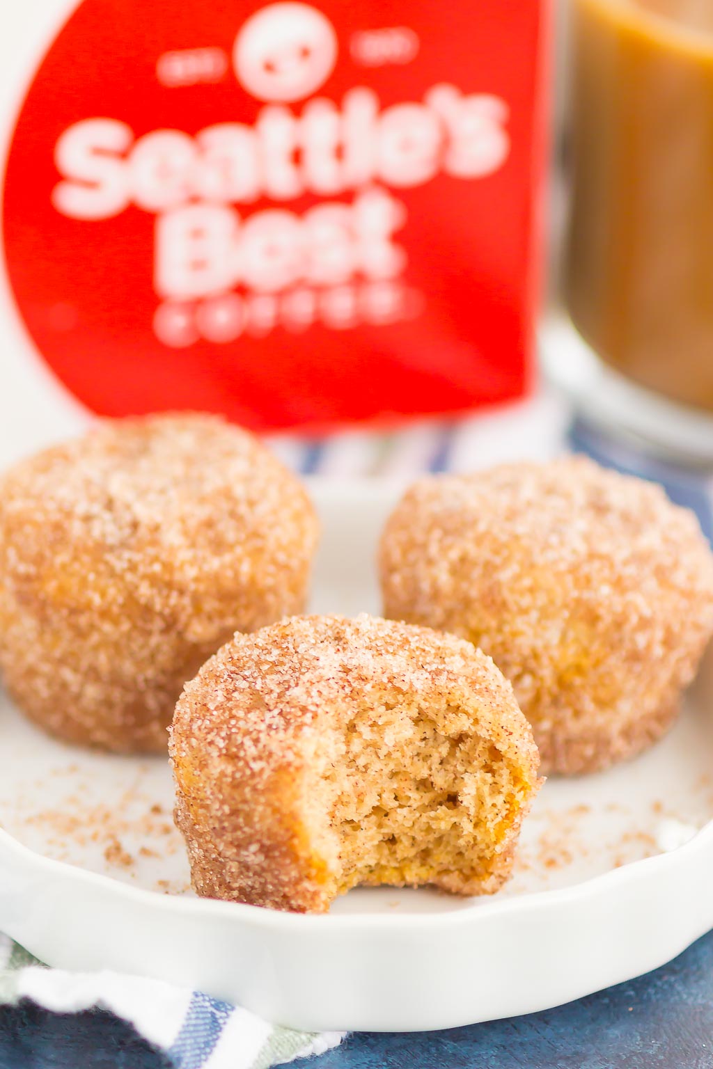 three homemade donut holes on a white plate. one has a bite missing. 