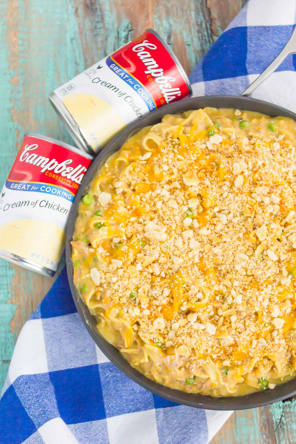 overhead view of cheesy tuna casserole in a large skillet next to two cans of Campbell's soup
