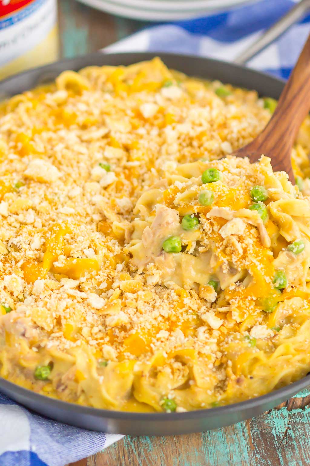 close up of cheesy tuna noodle casserole being scooped out of a large skillet 