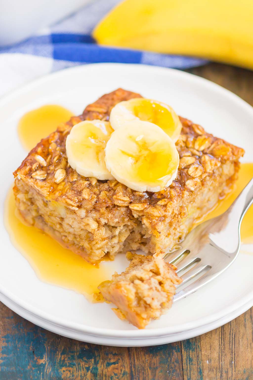 slice of banana baked oatmeal drizzled with honey on white plate with fork