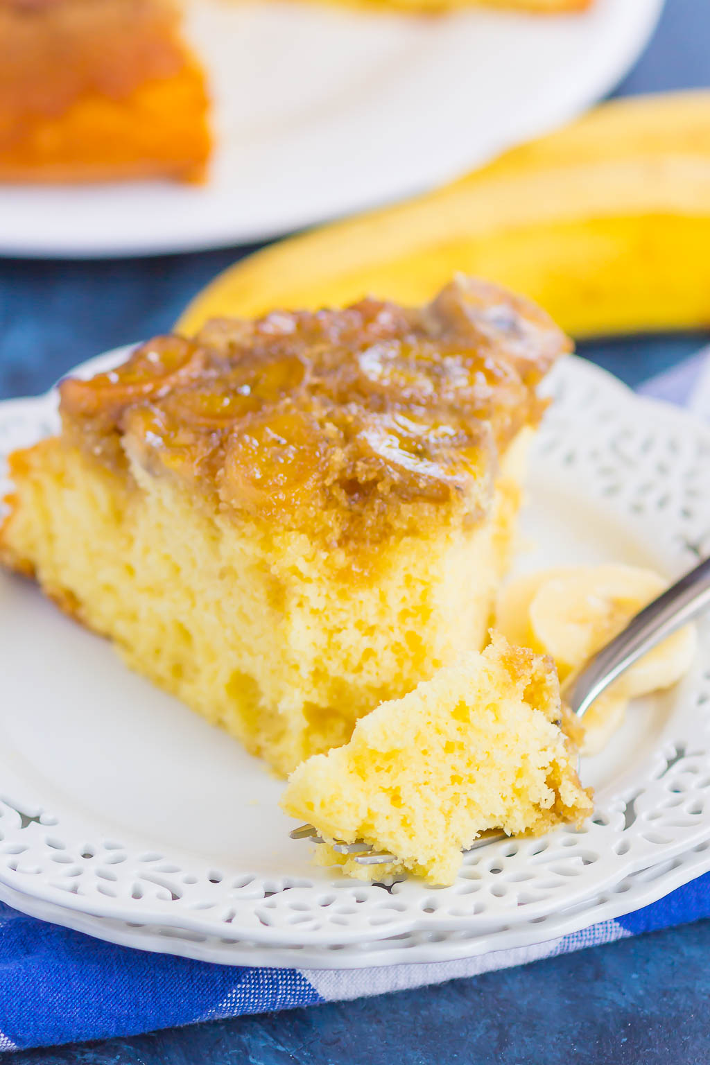 slice of banana upside down cake on a white plate with a fork. 