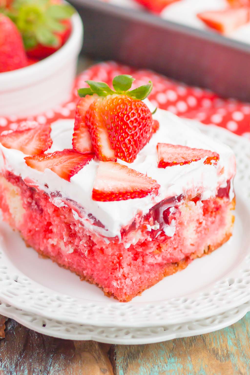 A strawberry jello cake on a white dessert plate. 