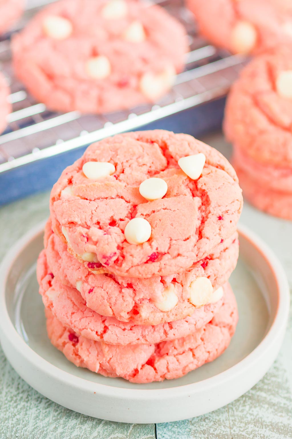 stack of strawberry cake mix cookies on white plate in front of cooling rack