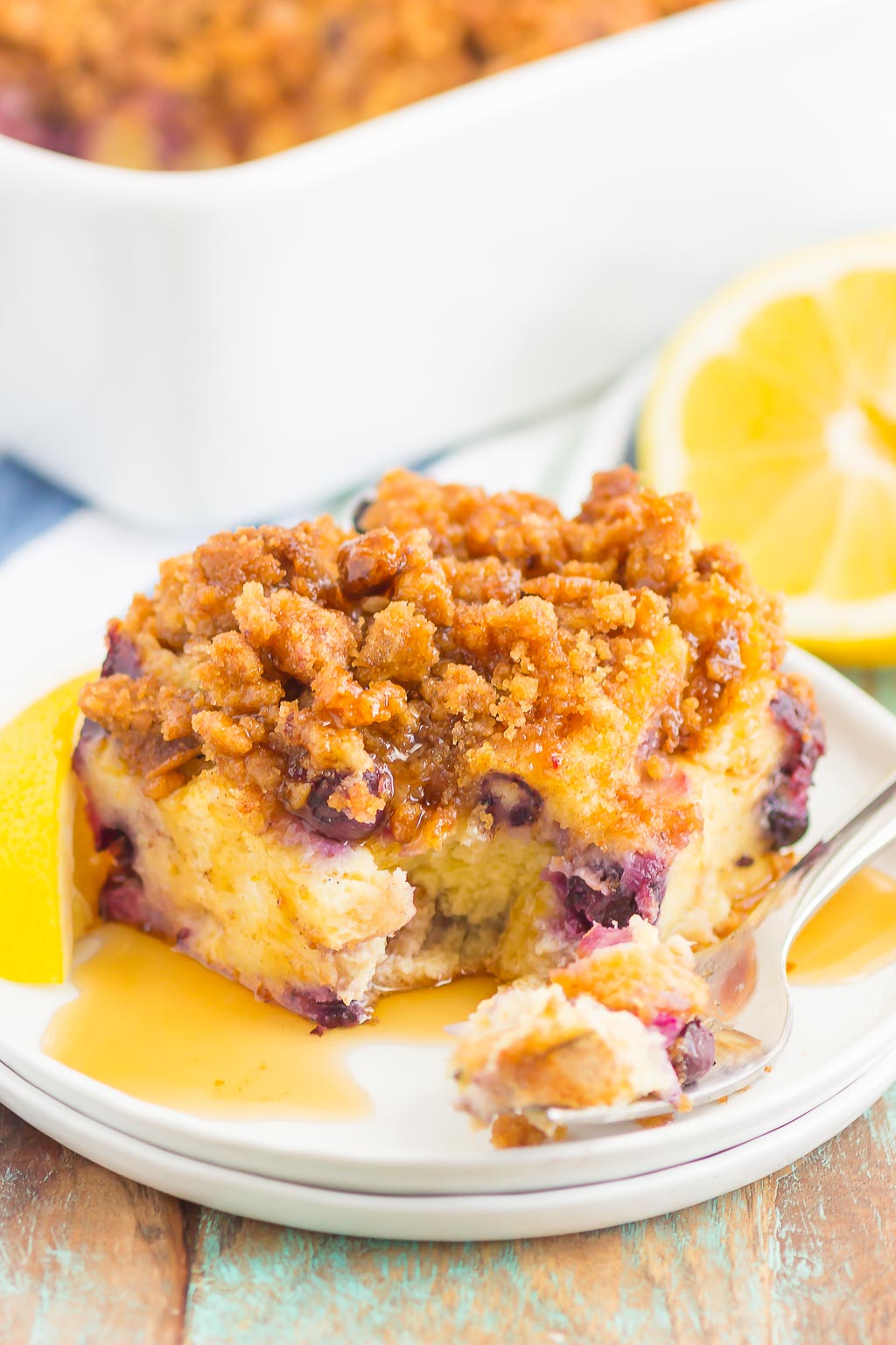 A slice of lemon blueberry french toast bake on a white dessert plate. A fork also rests on the plate. 