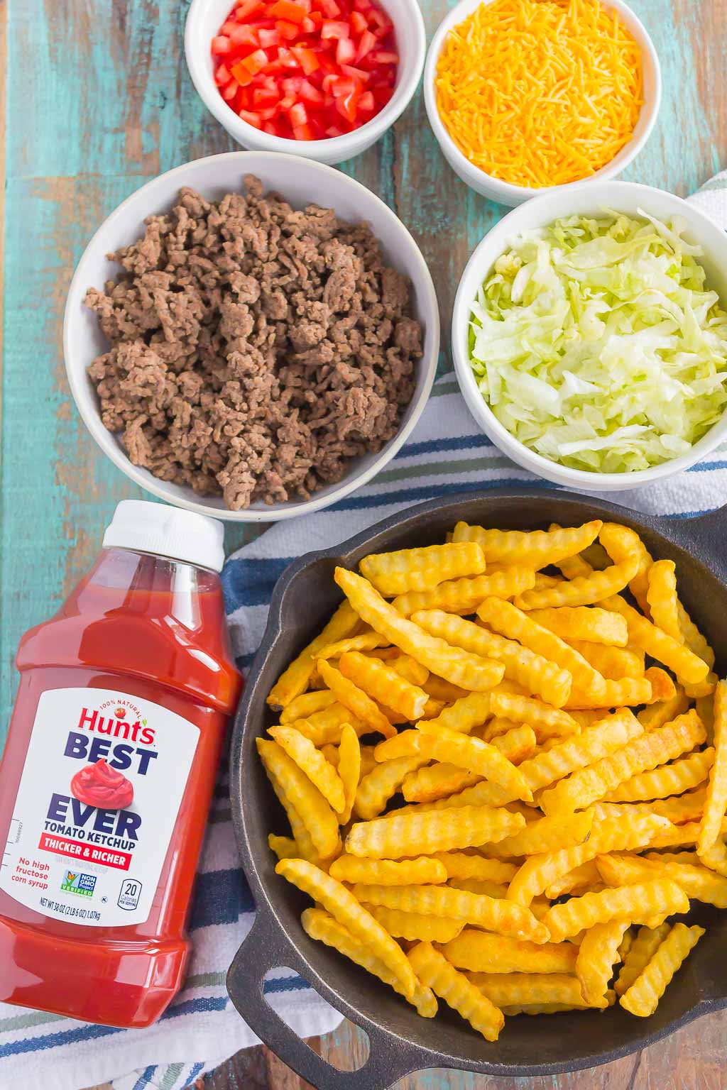 Loaded Cheeseburger Fries taste just like your favorite burger, but in appetizer form. These fries are topped with the classic ingredients of a cheeseburger and are baked to perfection. Easy to make and even better to eat, you'll love the crispy, crunchy, cheesy taste of this fun snack! #fries #cheeseburgerfries #loadedfries