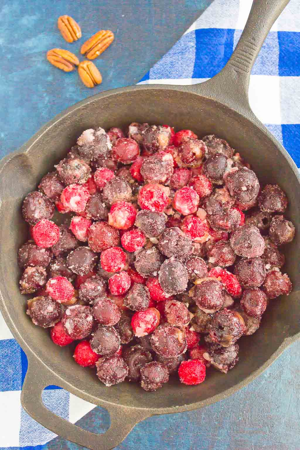 Overhead view of frozen cherries in a cast iron skillet. 