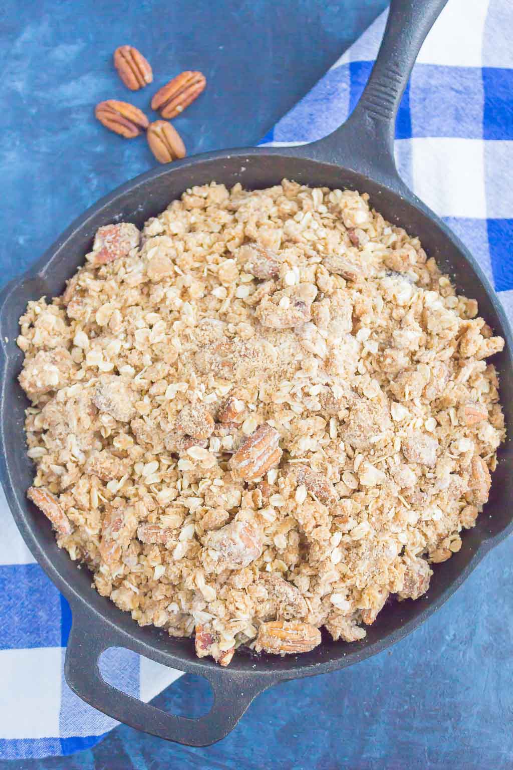 Overhead view of an unbaked fruit crisp in a cast iron skillet. 