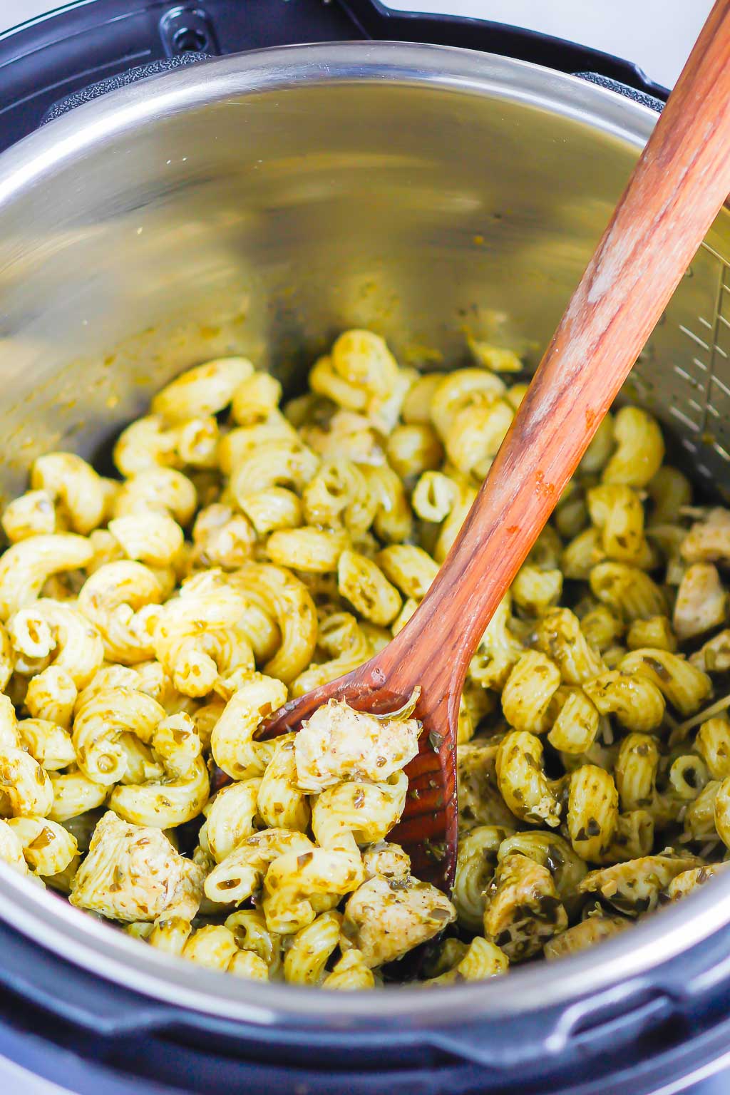 Instant Pot chicken and pasta being stirred with a wooden spoon 