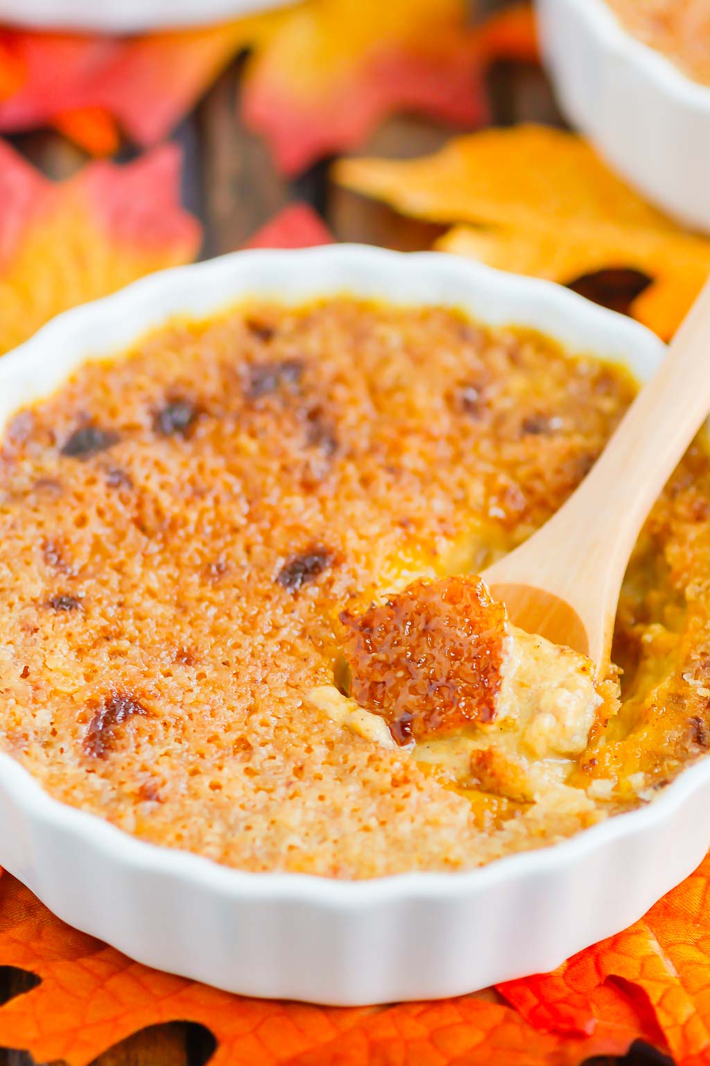 pumpkin creme brulee in a white ramekin with a wooden spoon