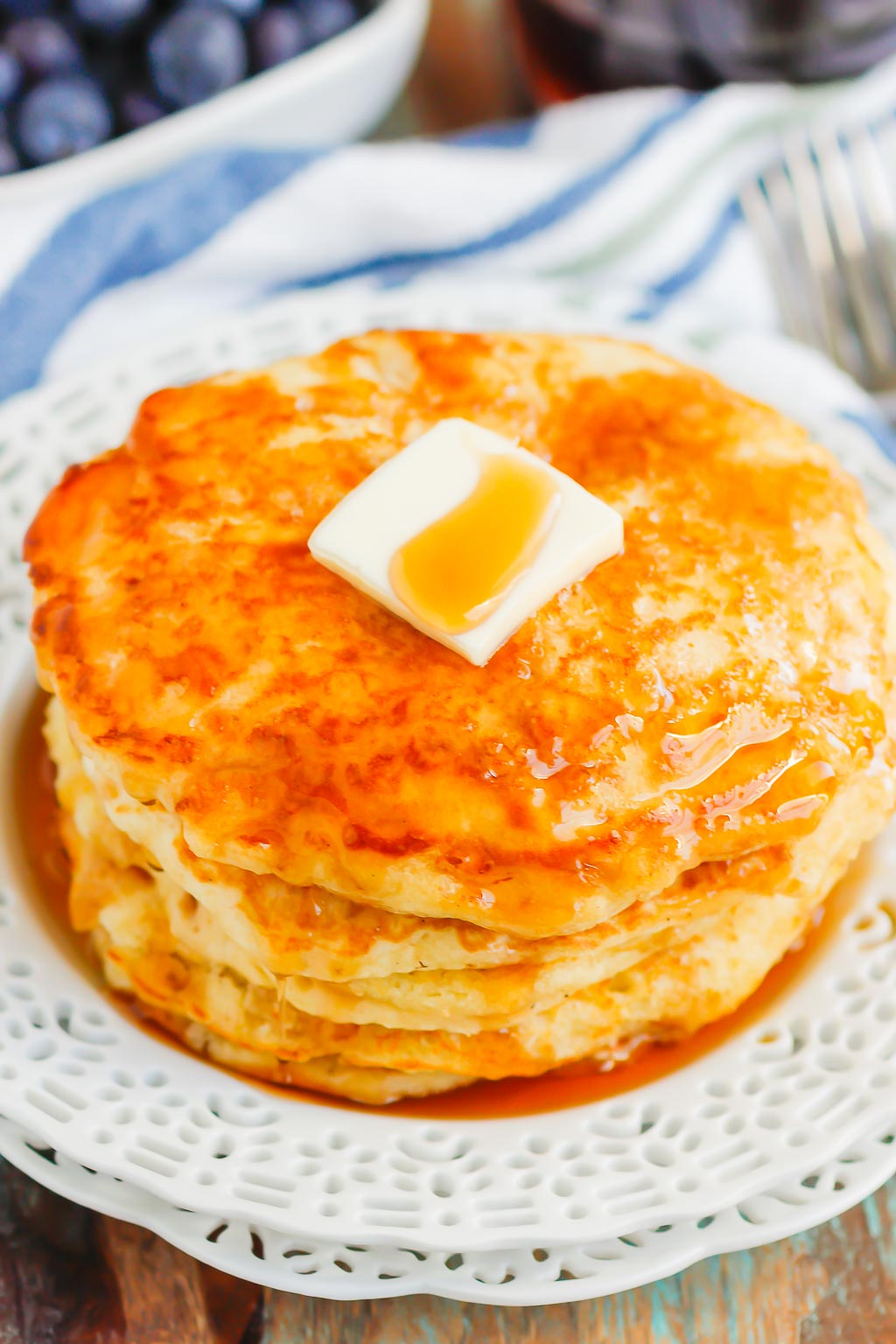 stack of fluffy buttermilk pancakes topped with butter and maple syrup