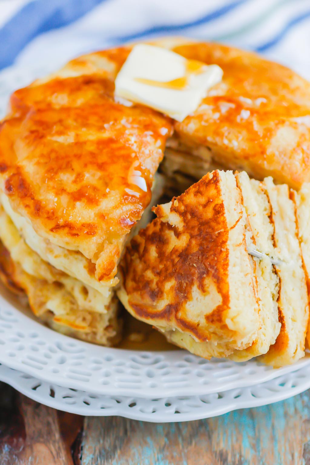 stack of buttermilk pancakes on white plate that have been cut into