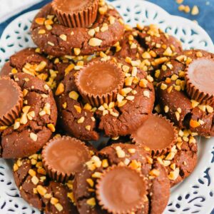 This fun spin on Chocolate Peanut Butter Blossoms adds even more chocolate and peanut butter flavor in every bite. This easy cookie recipe is soft, chewy, and all around delicious! #cookies #chocolatecookies #peanutbuttercookies #peanutbutterblossoms #blossomcookies #cookierecipe #holidaycookies #christmascookies #dessert