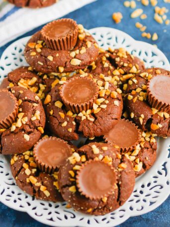 This fun spin on Chocolate Peanut Butter Blossoms adds even more chocolate and peanut butter flavor in every bite. This easy cookie recipe is soft, chewy, and all around delicious! #cookies #chocolatecookies #peanutbuttercookies #peanutbutterblossoms #blossomcookies #cookierecipe #holidaycookies #christmascookies #dessert