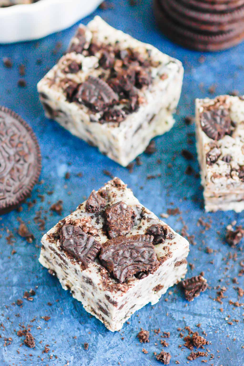 two pieces of cookies and cream fudge on a blue surface 