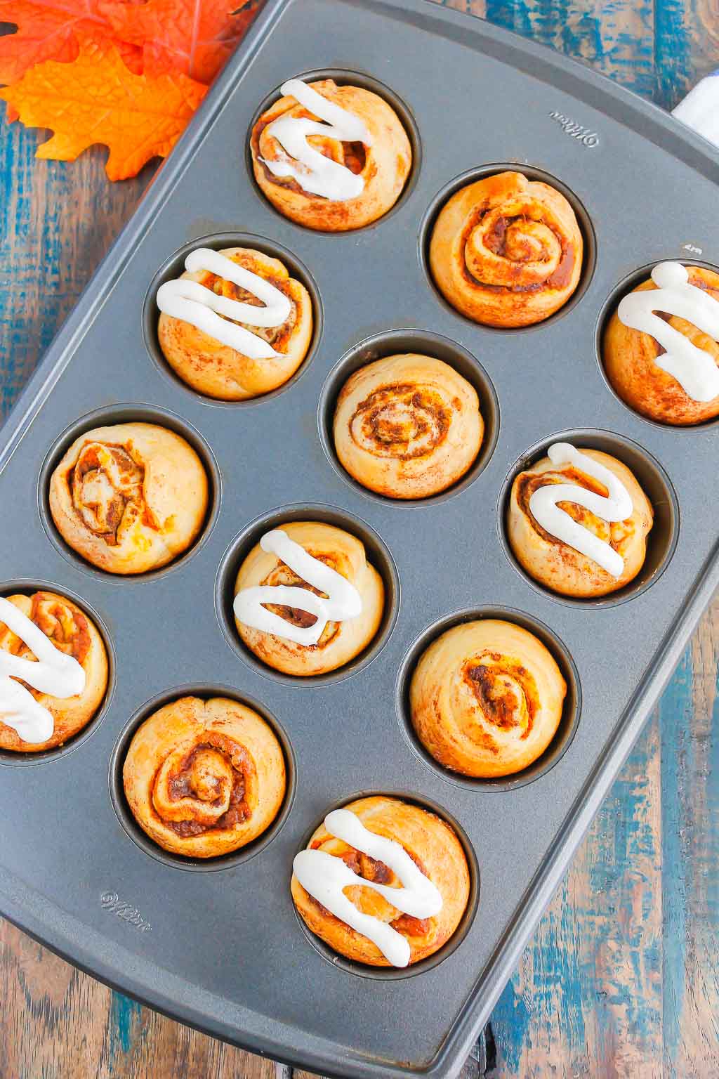 Overhead view of pumpkin pie cinnamon rolls in a muffin tin. 