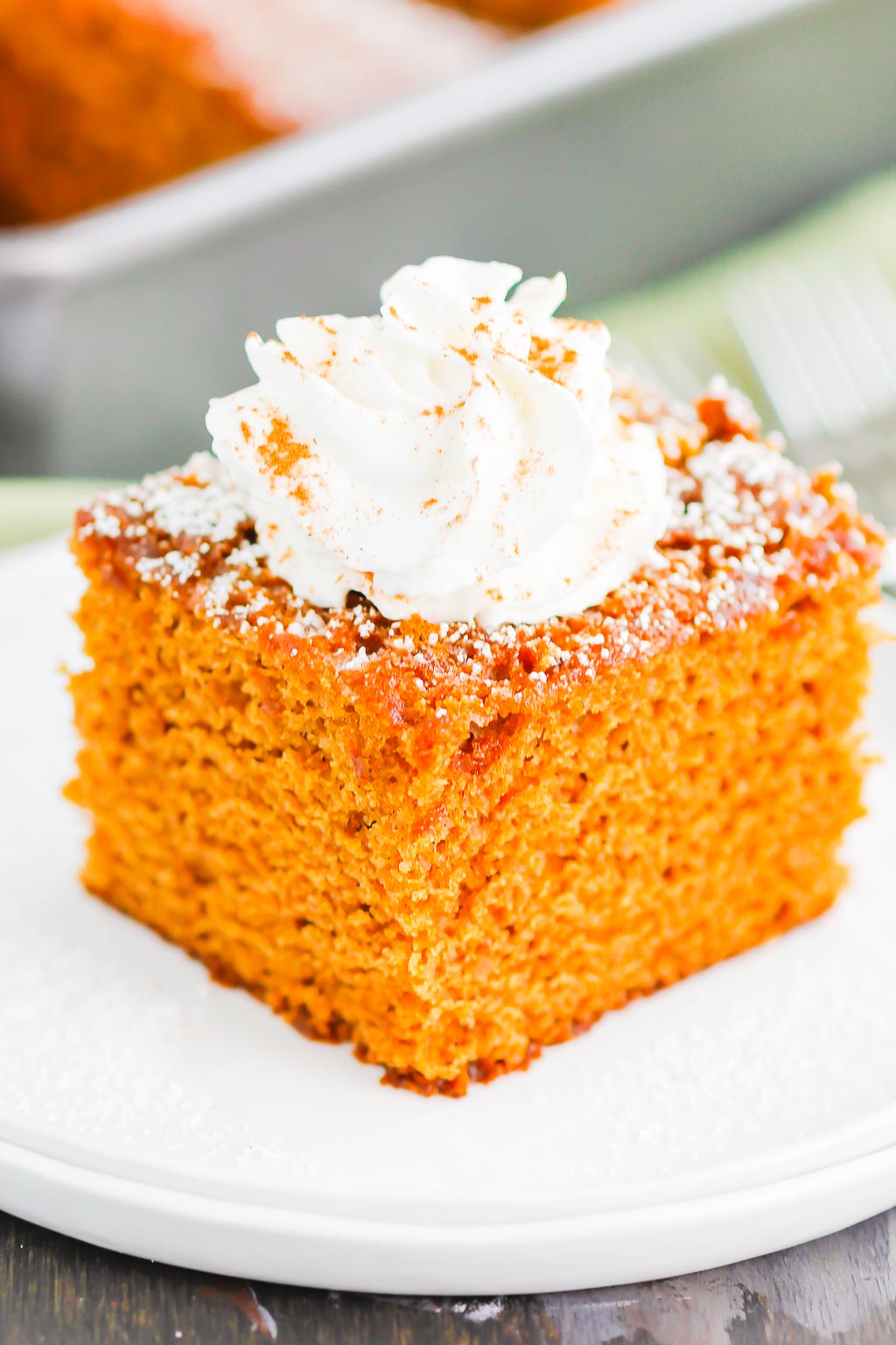 a slice of gingerbread cake topped with whipped cream on a white plate. 