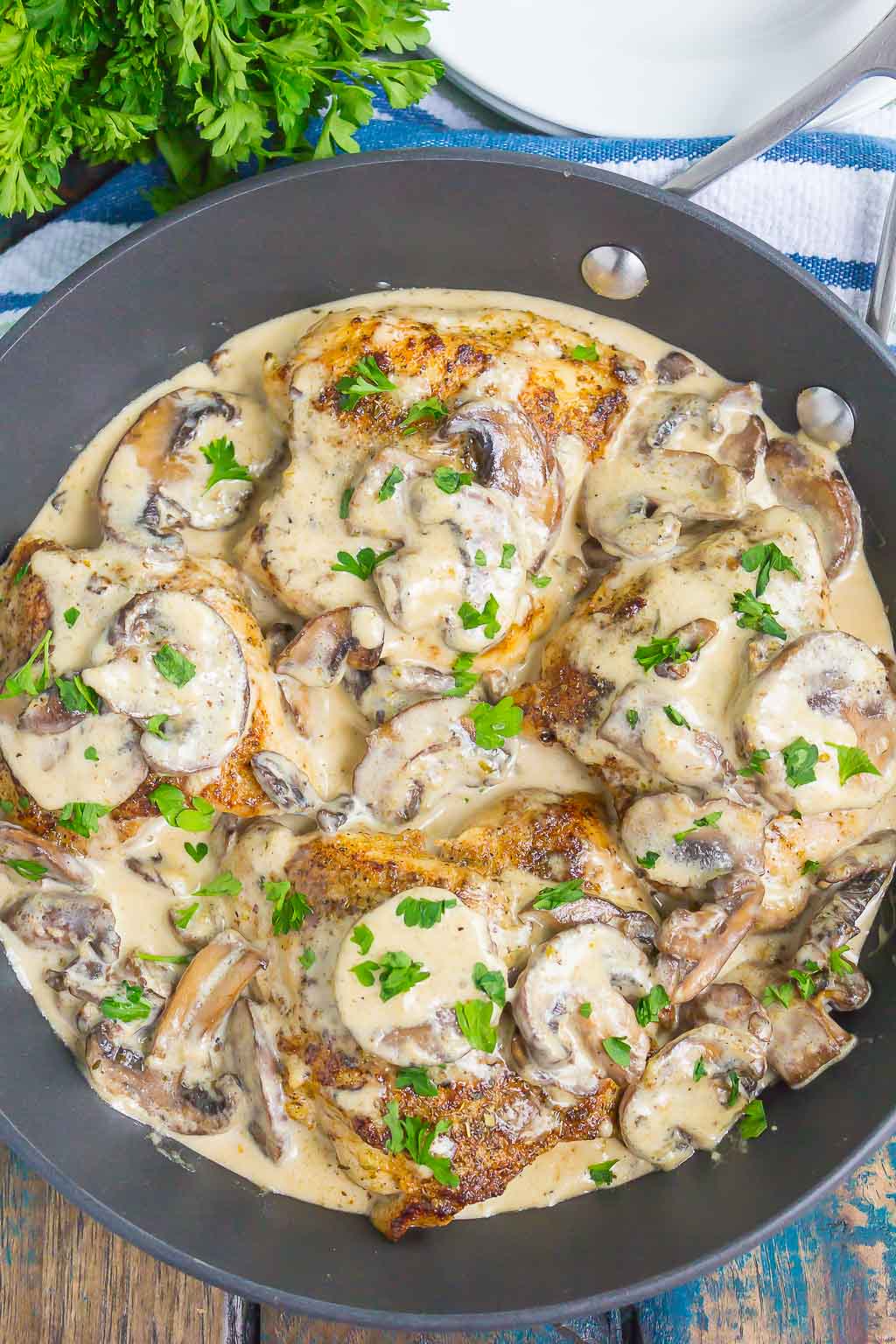 overhead view of creamy parmesan chicken with mushroom sauce in a skillet 