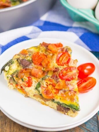 This Bacon and Tomato Frittata is a simple dish that's ready in less than an hour. Filled with crisp bacon, tender mushrooms, spinach and tomatoes, this recipe makes a delicious breakfast or brunch! #frittata #frittatarecipe #easyfrittata #bacon #baconfrittata #tomatofrittata #mushroomfrittata #breakfast #easybreakfast #breakfastrecipe