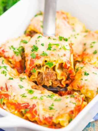lasagna rolls in a white dish with a spatula holding up one piece