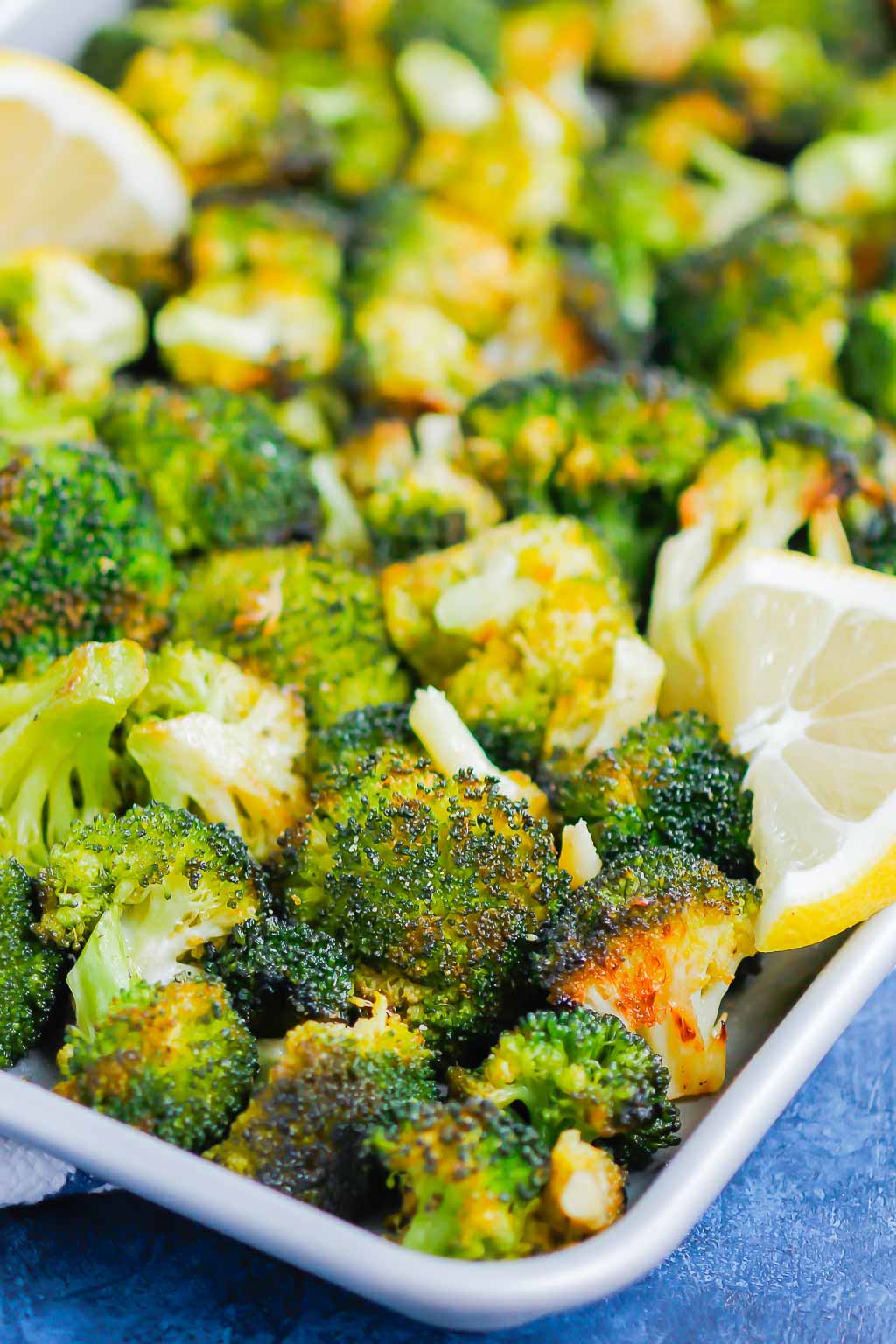 close up of roasted broccoli with lemon on a baking sheet