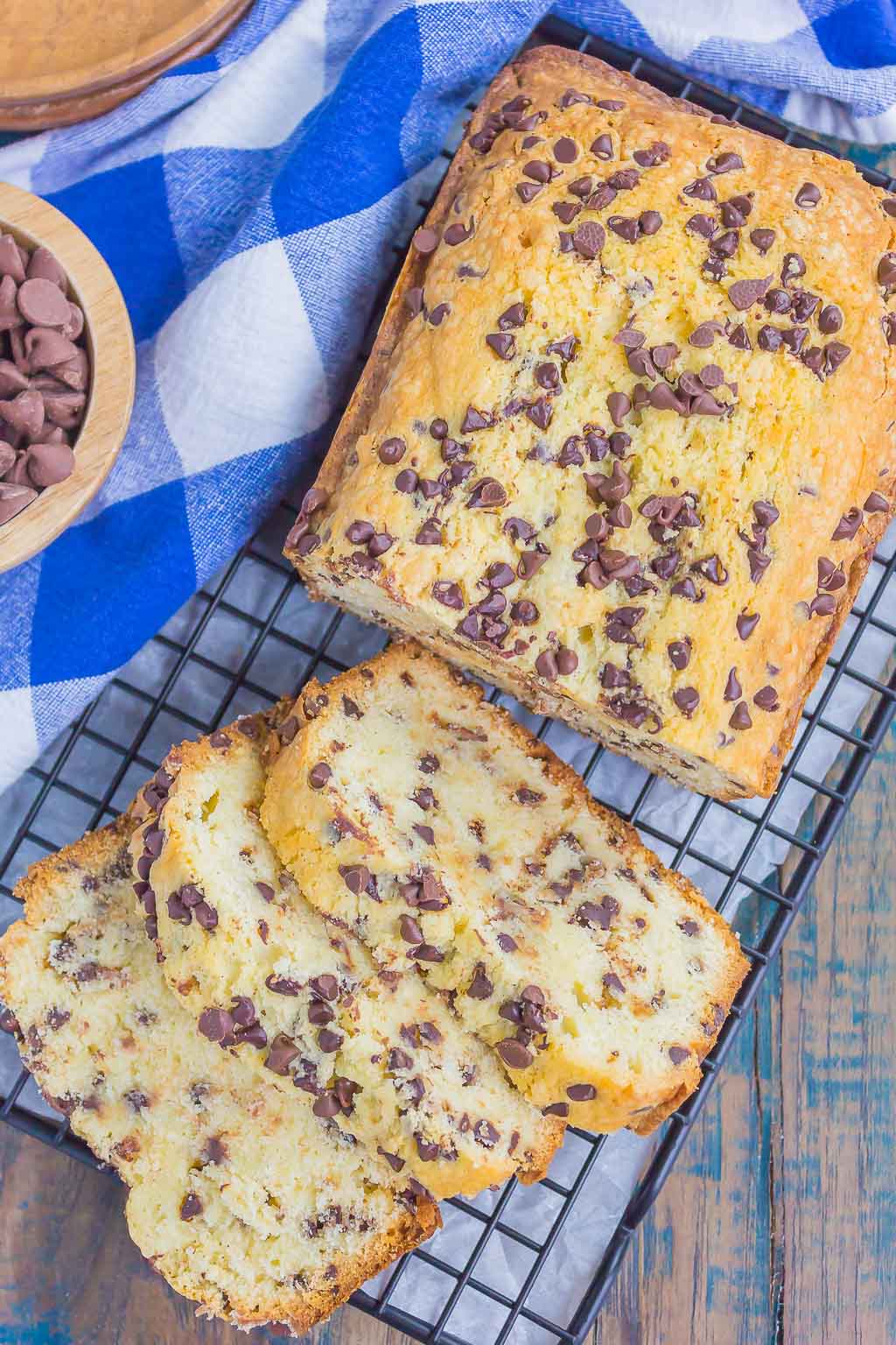 A homemade pound cake with chocolate chips on a wire cooling rack. Three slices have already been cut. 