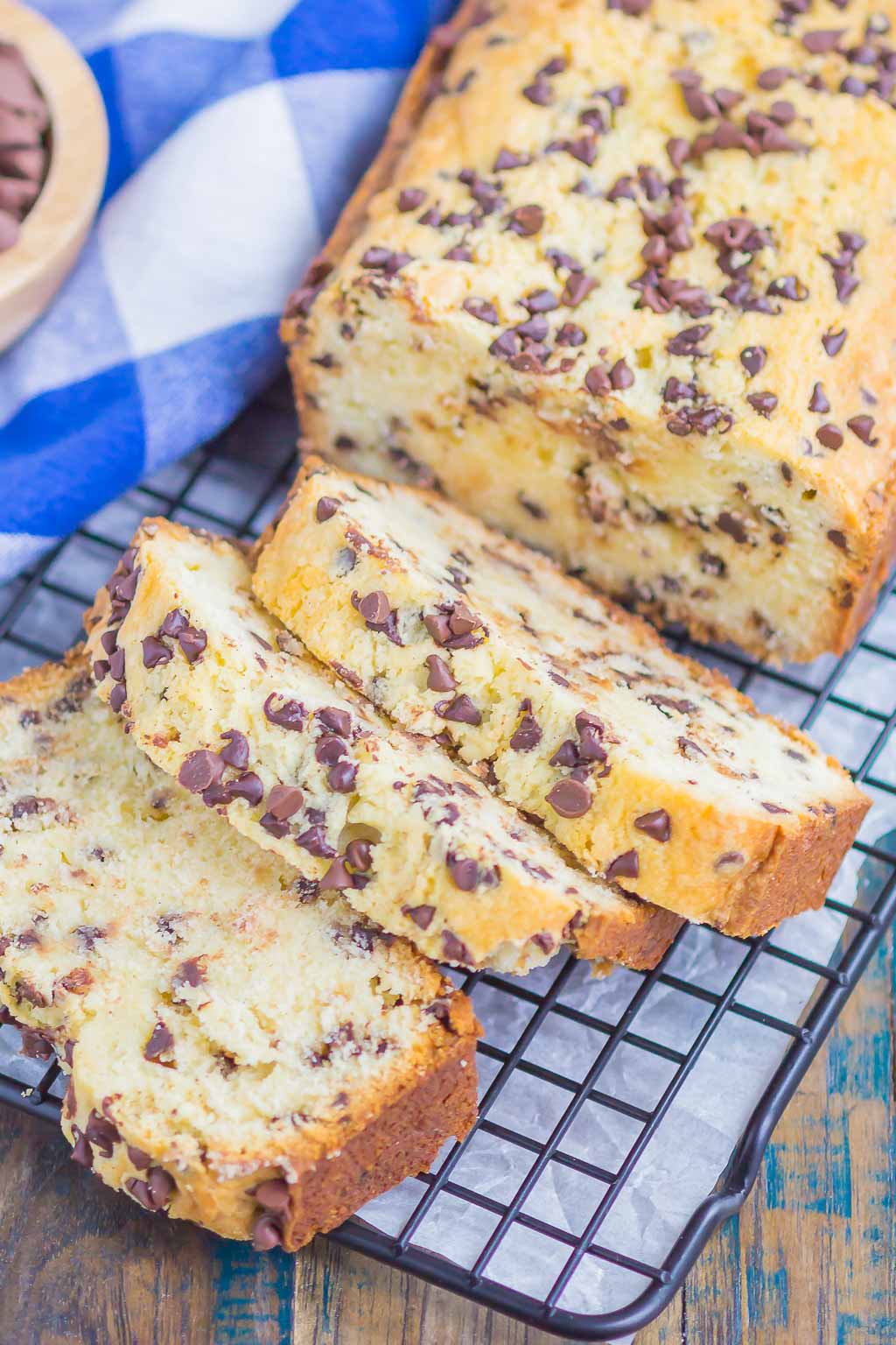 A homemade pound cake with chocolate chips on a wire cooling rack. Three slices have already been cut. 