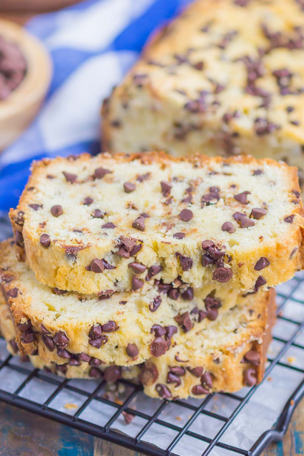 Two slices of chocolate chip pound cake on a wire cool rack. The rest of the cake is in the background. 