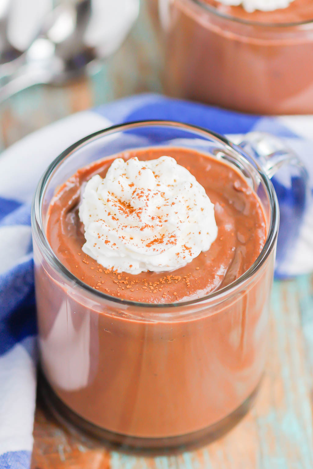 A glass jar of chocolate pudding from scratch, topped with whipped cream. 