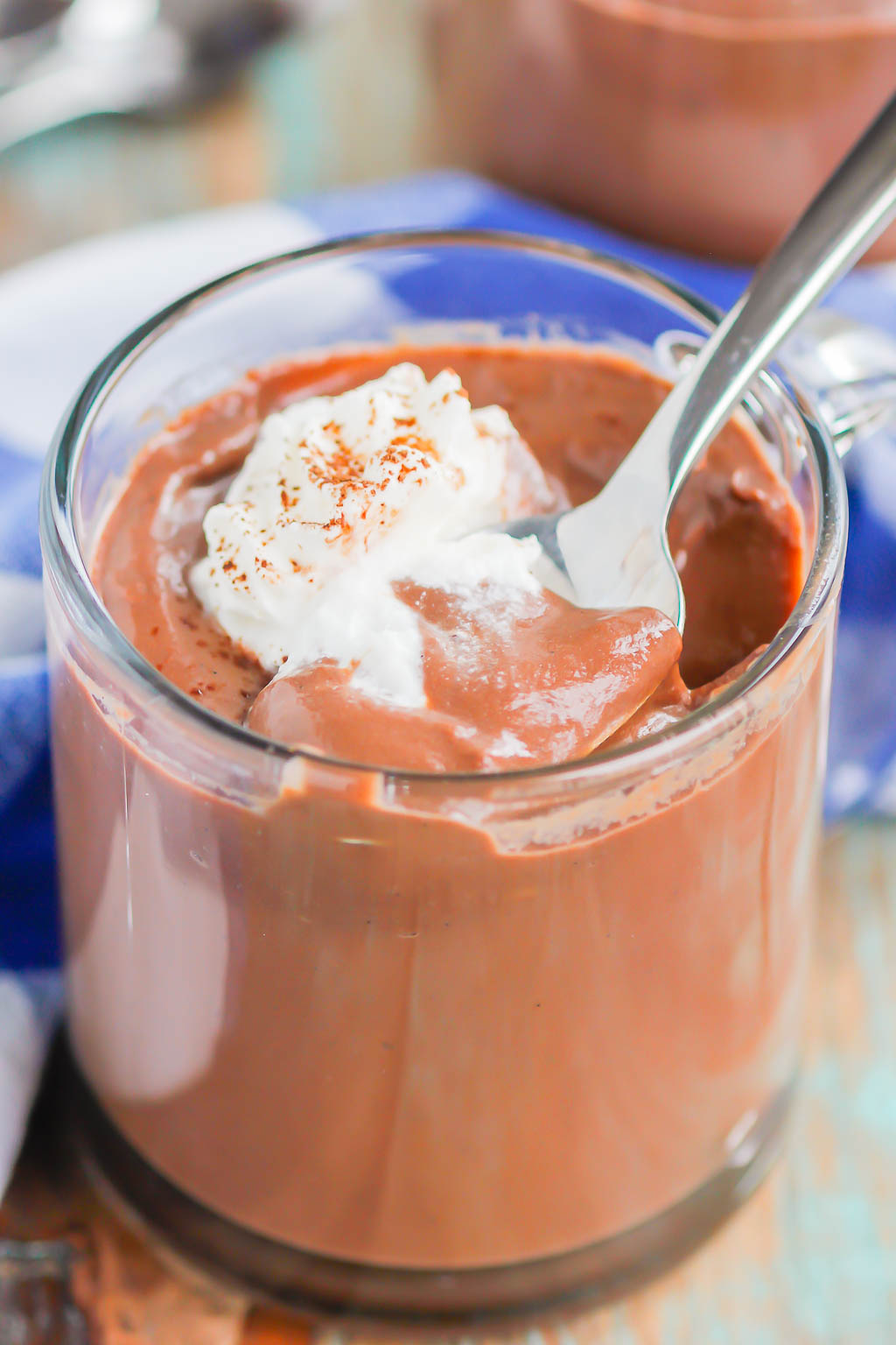 A spoon being dug into a glass jar of the best chocolate pudding. 