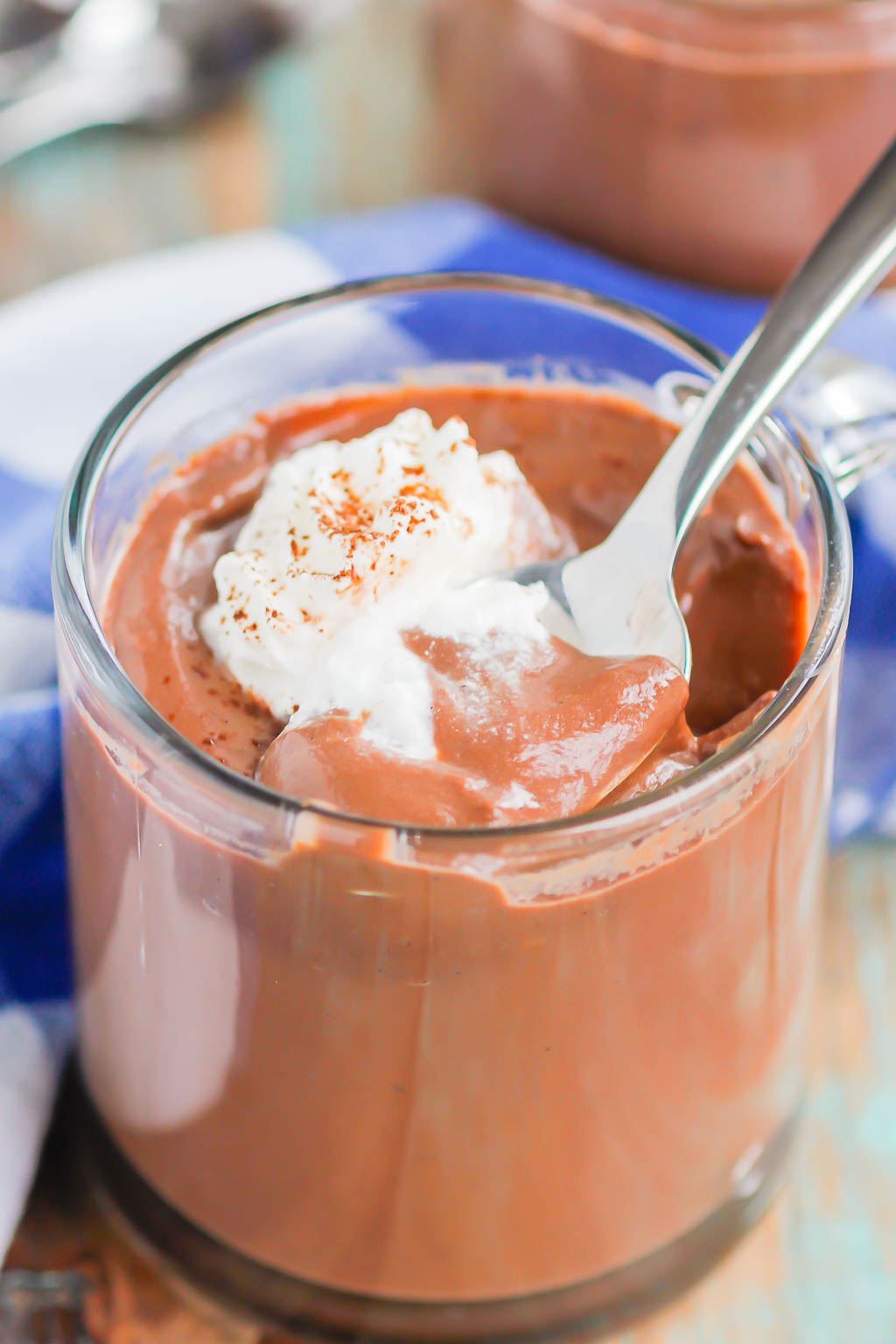 A spoon digging into a glass jar of homemade chocolate pudding. 