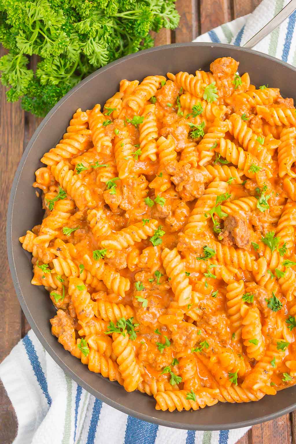 overhead view of ground beef pasta in skillet on striped tea towel