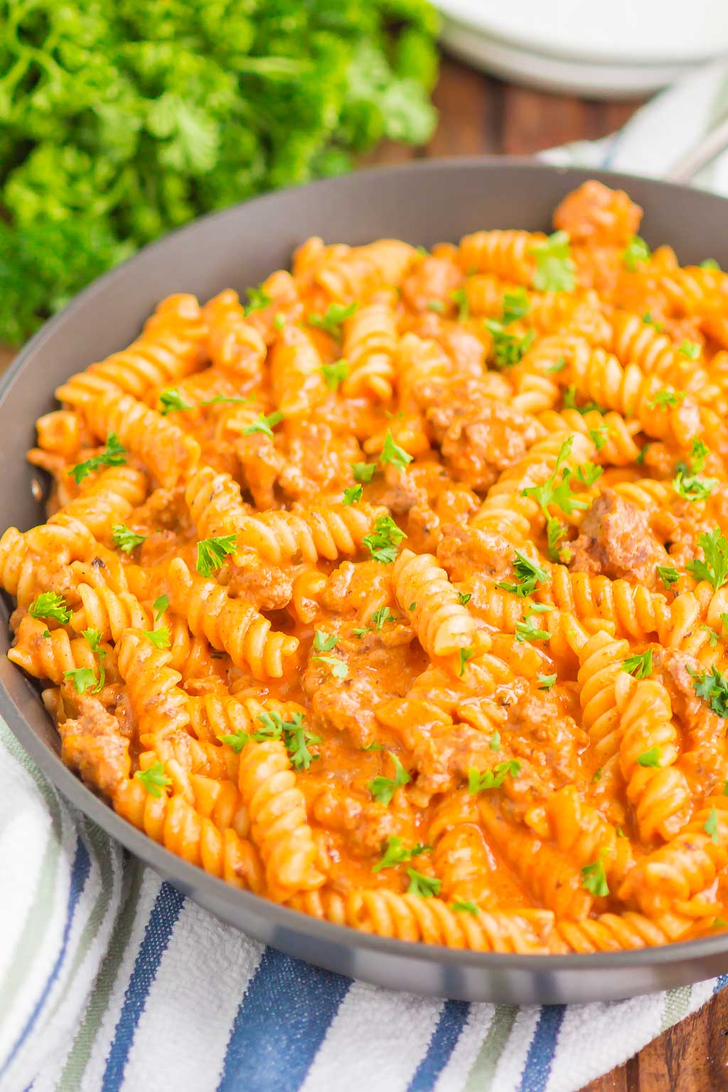 ground beef pasta in a skillet next to bunch of parsley