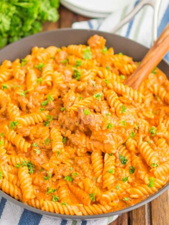 pasta in a black skillet with a wooden spoon