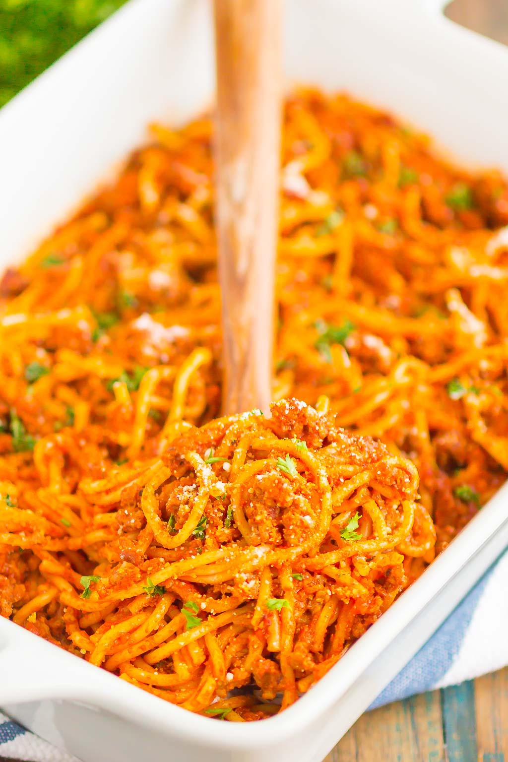Easy Baked Spaghetti in a casserole dish. a wooden spoon is inserted in the casserole. 