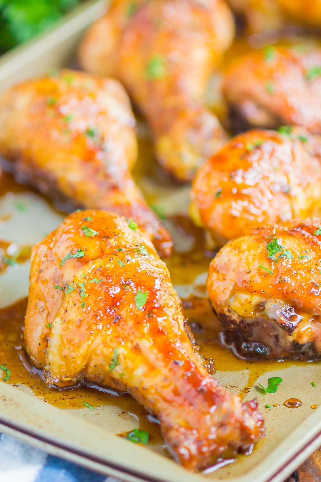Close up of baked chicken legs topped with a honey-soy glaze on a baking sheet. 