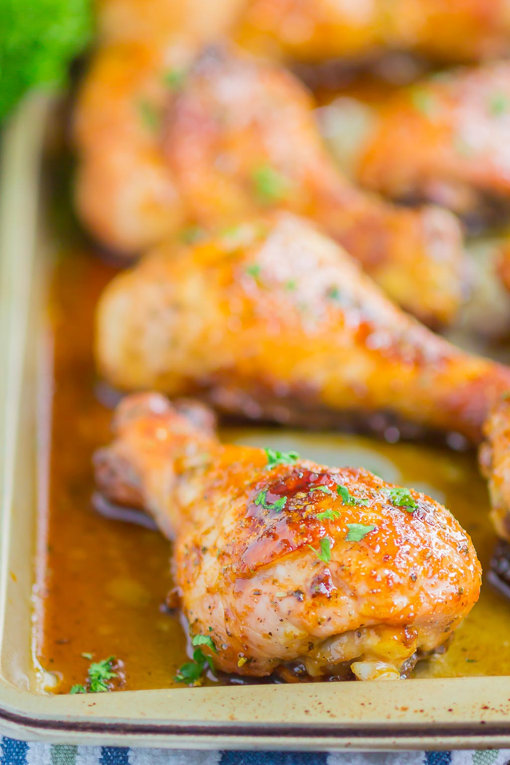 A side view of baked chicken drumsticks on a baking sheet. 
