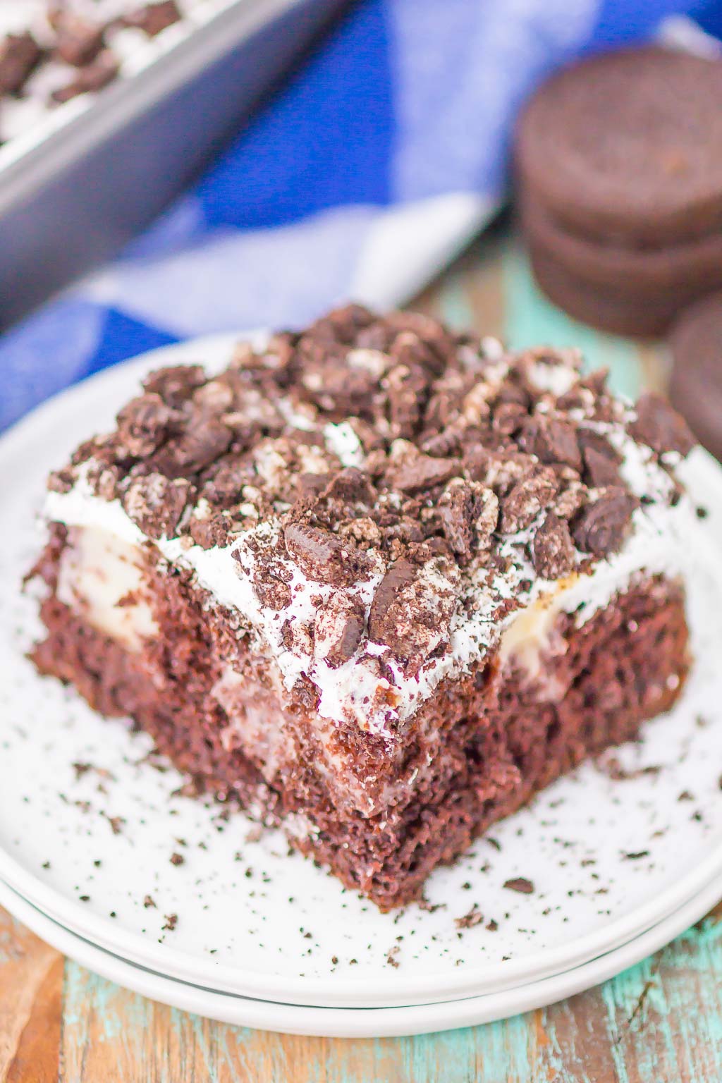 A slice of Oreo poke cake on a speckled dessert plate. 