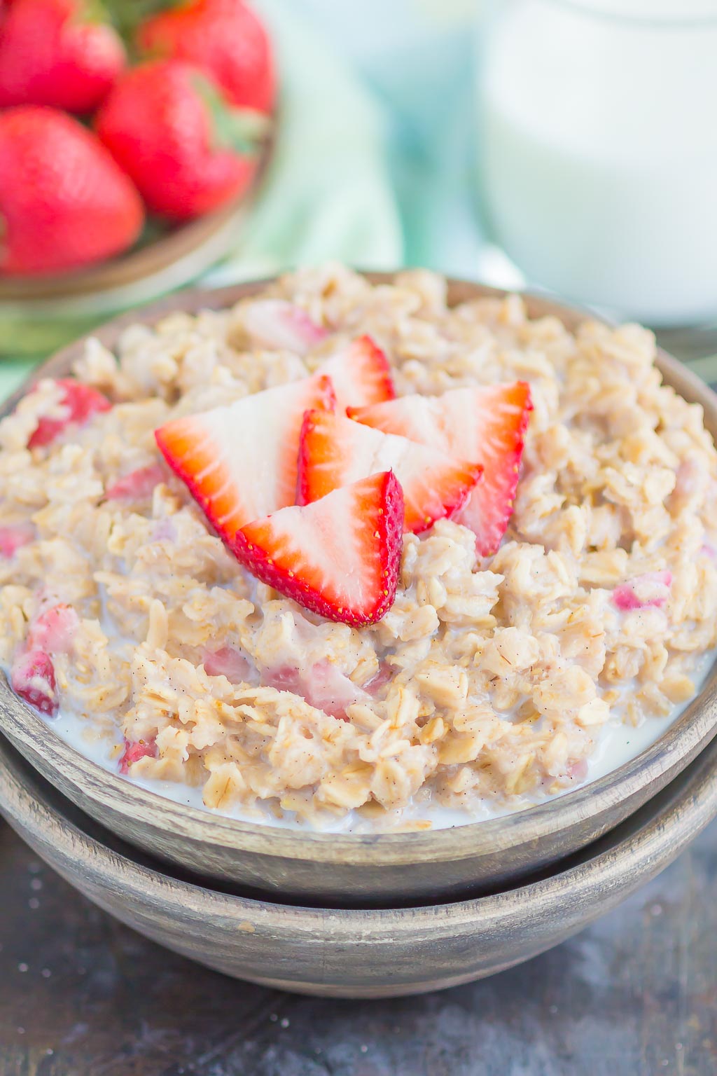 A bowl of strawberries and cream oatmeal, garnished with fresh strawberry slices. 