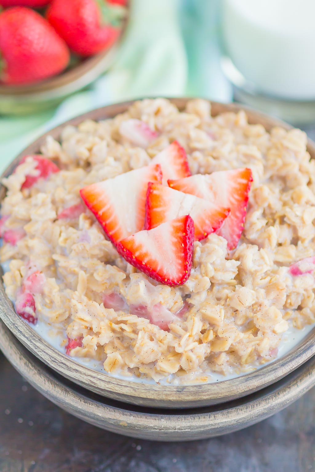 A bowl of strawberries and cream oatmeal, garnished with fresh strawberry slices. 