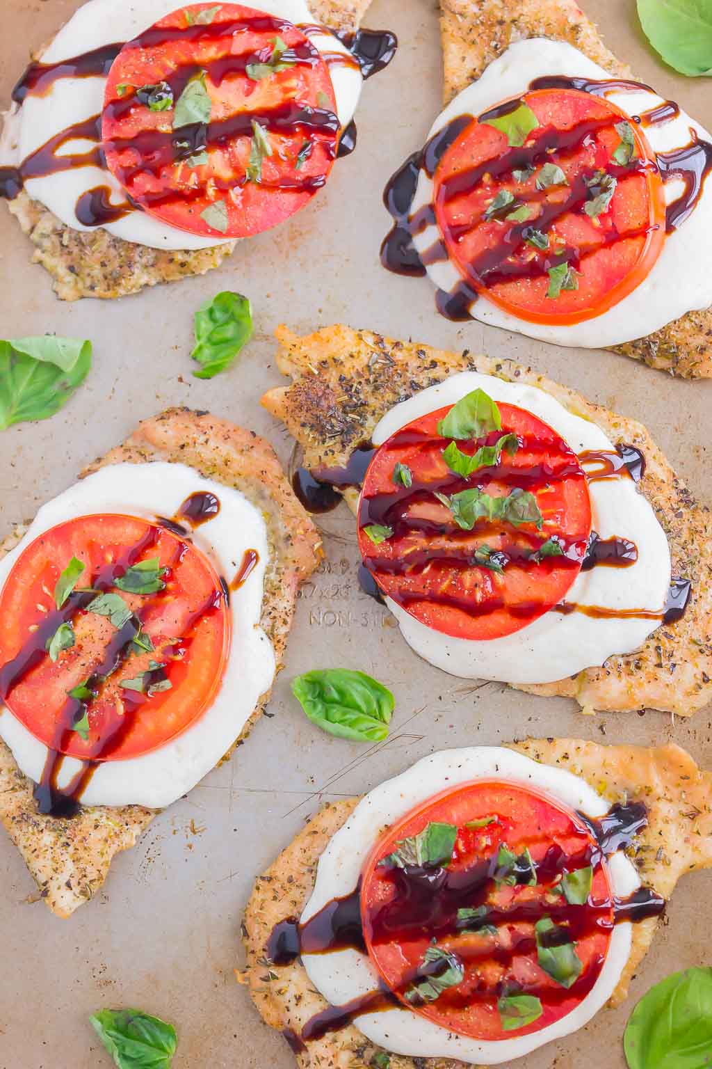 Overhead view of Baked balsamic Caprese Chicken breasts on a baking sheet 