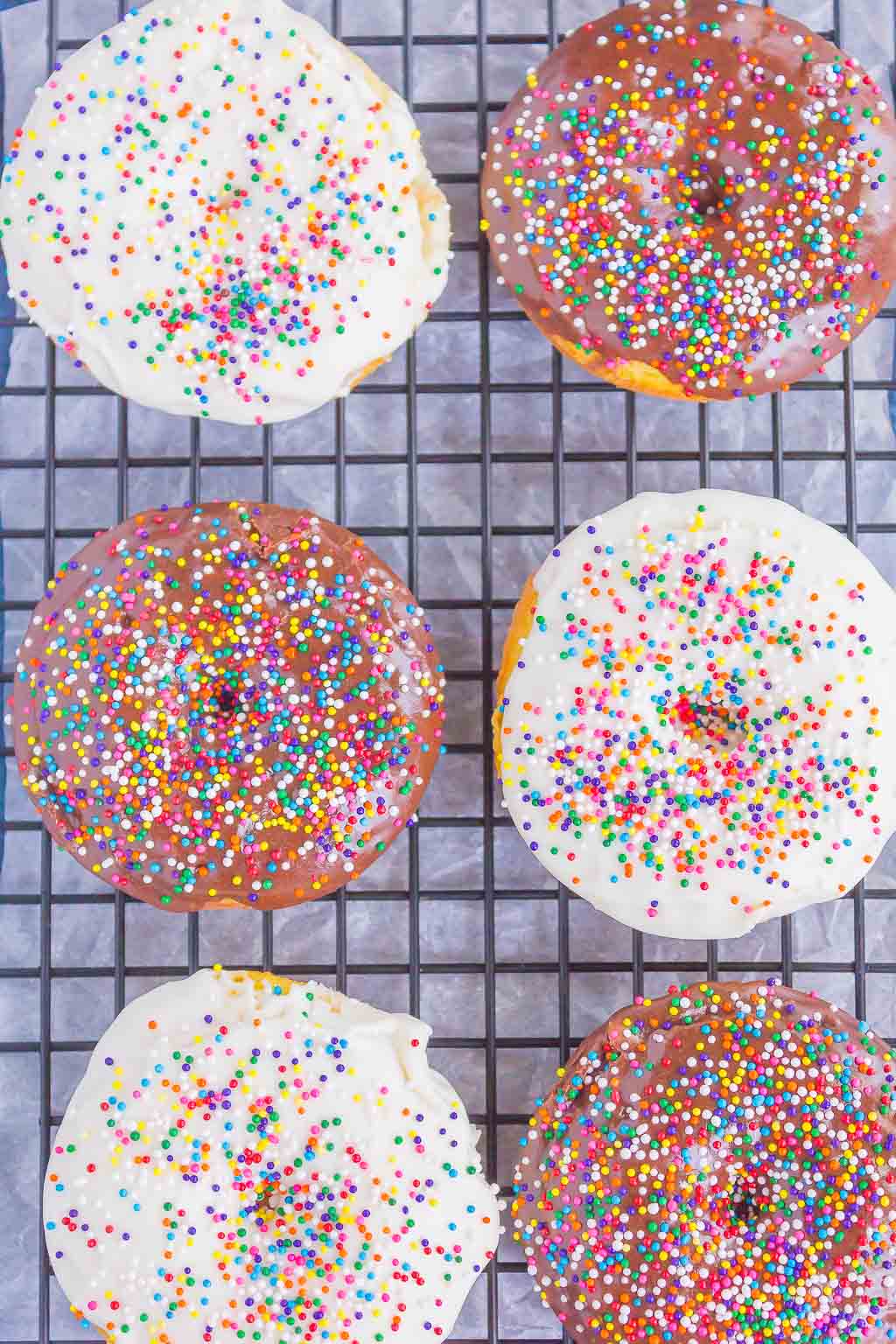 Overhead view of six frosted cake batter donuts on a wire cooling rack. 