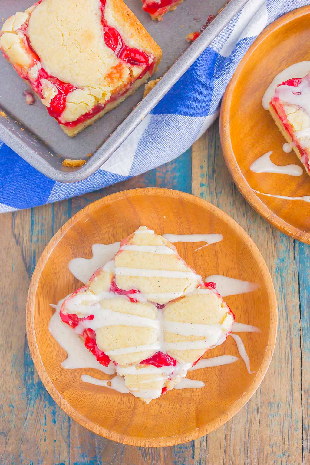 Overhead view of two wood plates and a metal baking sheet with cherry pie bars. 