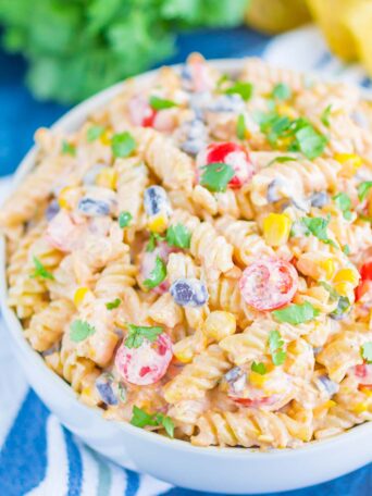 Taco Pasta Salad is loaded with Mexican flavors and ready in no time. With a creamy, zesty dressing and all of your favorite toppings, this easy pasta salad is perfect for your next party!