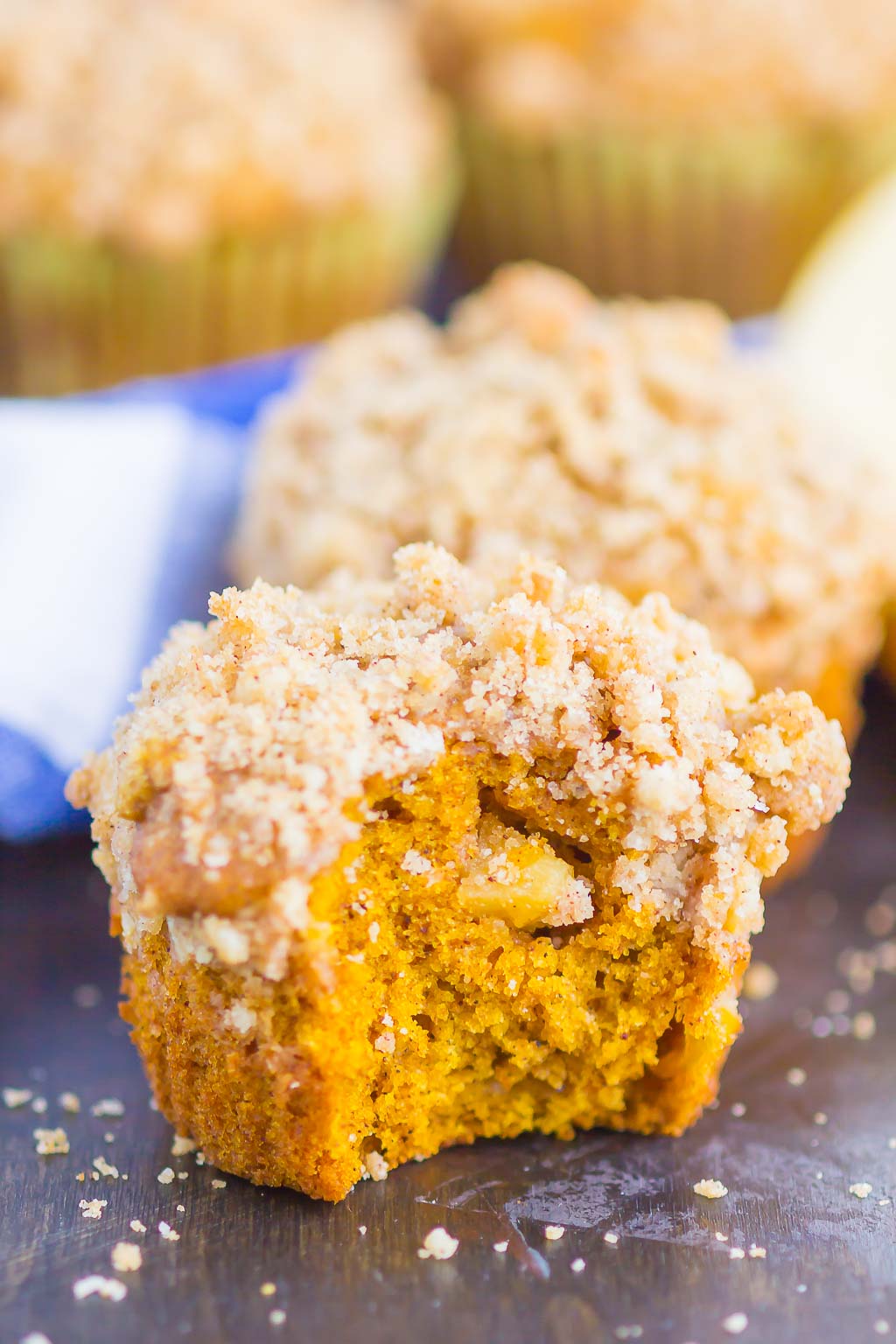 Two Pumpkin Apple Muffins, the front muffin has a bite missing. 