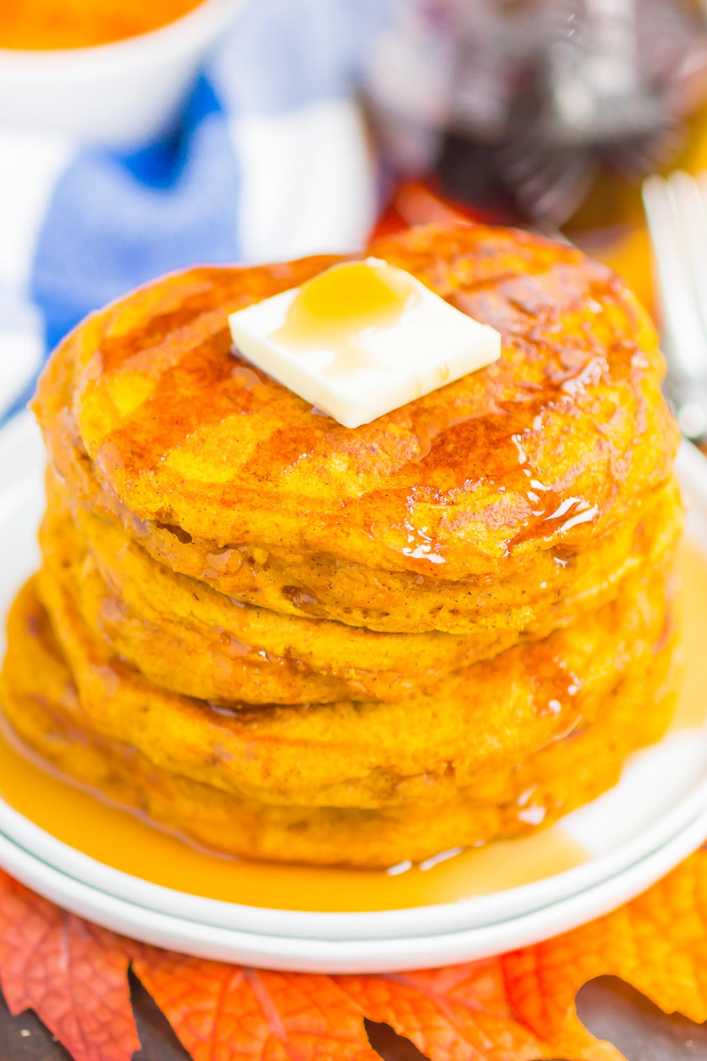 a stack of Pumpkin Spice Pancakes topped with a pat of butter and maple syrup