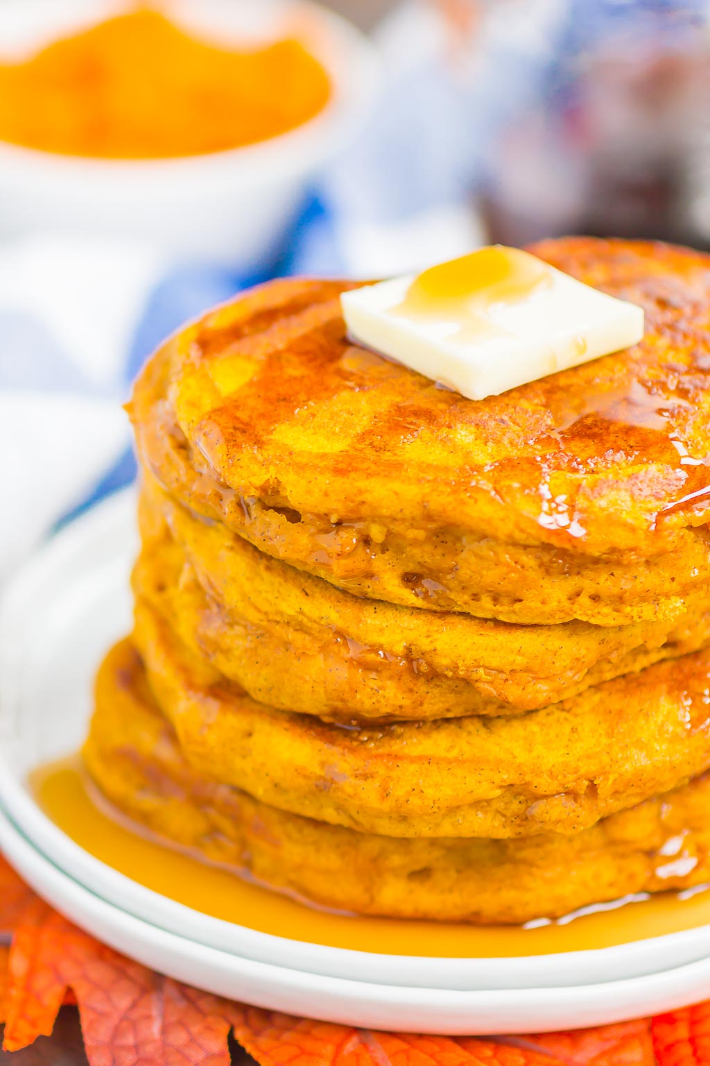 a stack of Pumpkin Spice Pancakes topped with a pat of butter and maple syrup