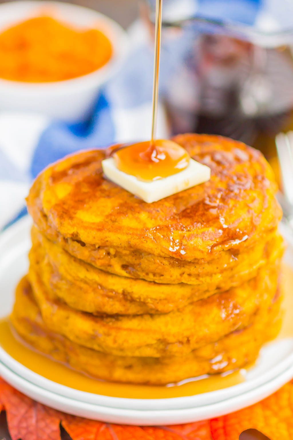 a stack of Pumpkin Spice Pancakes being drizzled with maple syrup 
